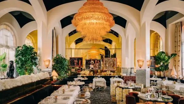 Un restaurant romantique à Paris, avec un lustre orange spectaculaire, des banquettes sombres, des tables dressées et des œuvres d'art.