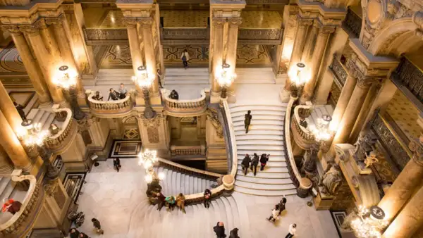 Vue aérienne de l'escalier monumental du Palais Garnier avec des visiteurs.