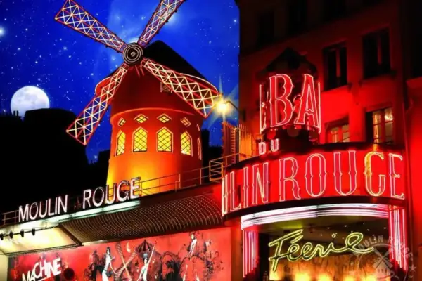 Le Moulin Rouge illuminé la nuit, avec son moulin rouge emblématique et ses néons. Le prix d'entrée pour ce spectacle légendaire est une invitation à la féerie.
