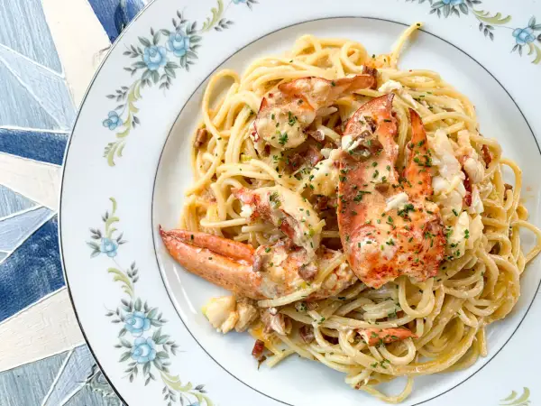 Délicieux spaghetti aux morceaux de homard, nappés d'une sauce crémeuse et parsemés de ciboulette. Un plat de pâtes au homard qui fait rêver.