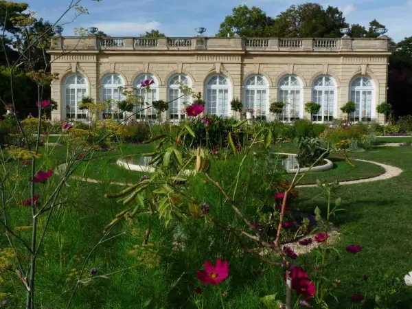 Jardin fleuri devant un bâtiment classique, avec des arches et des fenêtres, au Bois de Boulogne.