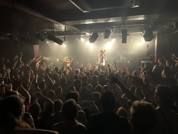 Foule en délire dans une salle de concert, le nombre de places semble limité mais l'ambiance est électrique.