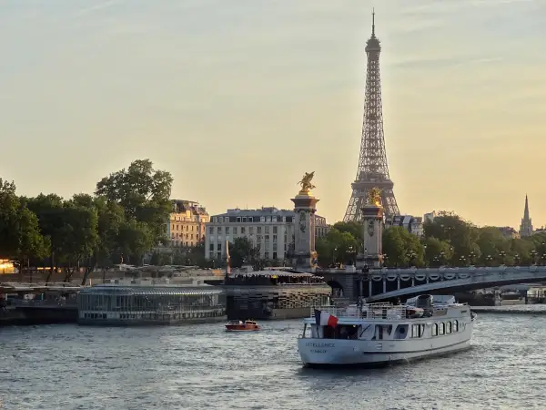 Une belle balade sur Seine à Paris, avec la Tour Eiffel et le pont Alexandre III en arrière-plan. Un bateau navigue paisiblement sur l'eau.