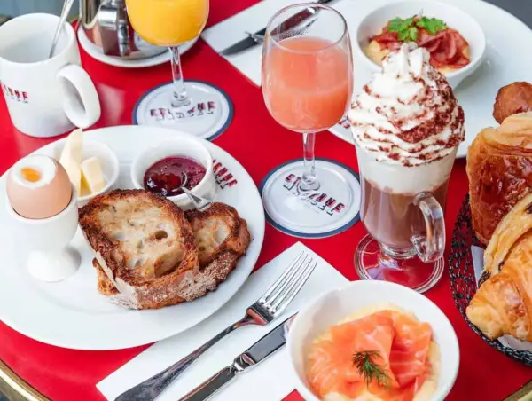 Un délicieux brunch avec enfants : toasts, œuf à la coque, confiture, jus d'orange, chocolat viennois et viennoiseries.