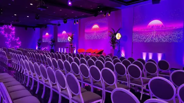 Un auditorium à Paris, baigné de lumières violettes, prêt pour un événement futuriste. Des rangées de chaises attendent les invités.