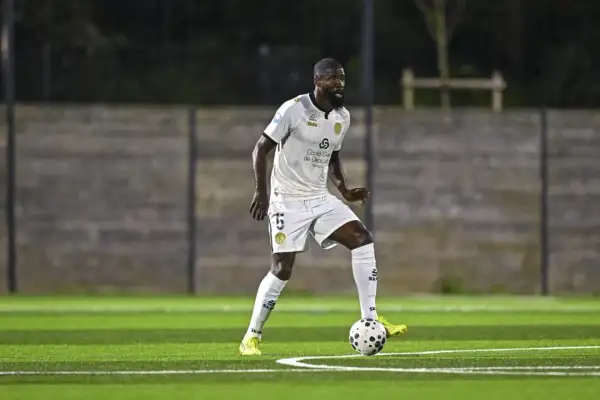 Joueur de football en action sur la pelouse du stade Charléty, concentré sur le ballon.
