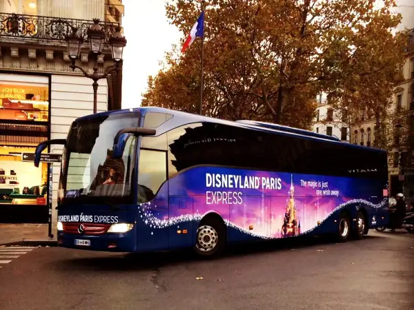 Un bus bleu "Disneyland Paris Express" circule dans Paris, prêt à emmener les visiteurs vers la magie.