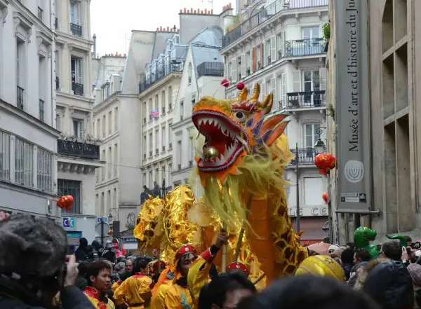 Un grand dragon doré danse dans les rues de Paris lors du défilé du nouvel an chinois, sous les regards émerveillés de la foule.