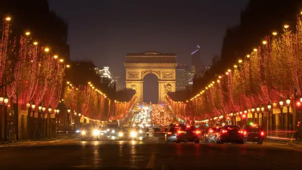 Les Champs-Élysées illuminés pour le réveillon de Noël, avec le trafic parisien et l'Arc de Triomphe en fond.