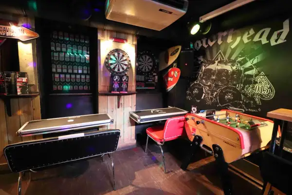 Ambiance de baby bar avec fléchettes, baby-foot et murs décorés de vinyles rock.
