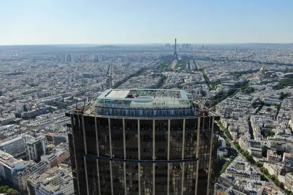 Vue aérienne de Paris depuis la **Tour Montparnasse**. Des visiteurs profitent de la vue panoramique sur la ville, avec la Tour Eiffel en toile de fond.