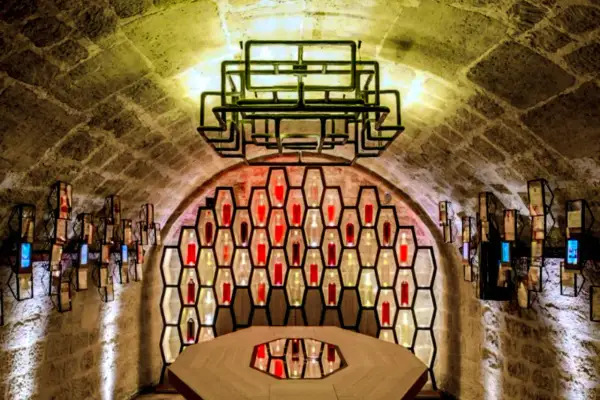 Ambiance unique aux Caves du Louvre, avis sur ce lieu historique et moderne. Bouteilles illuminées dans des alvéoles, table centrale.