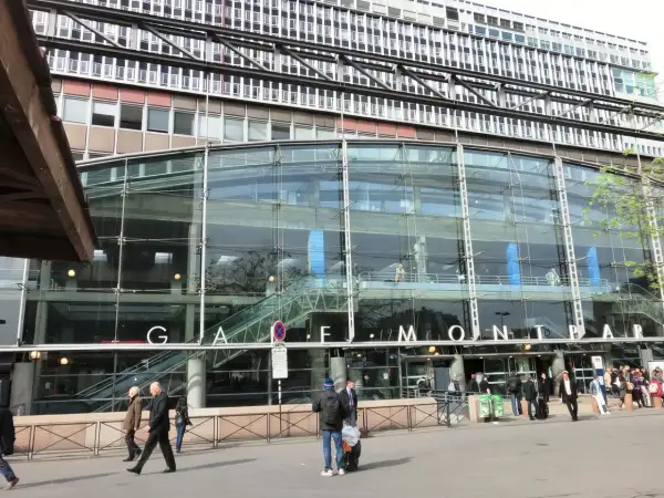 La gare de Montparnasse, avec sa façade de verre moderne, accueille des voyageurs pressés.