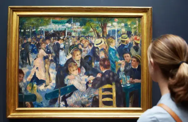 Une femme admire une peinture de Renoir représentant une scène animée de danseurs et de convives dans un jardin.